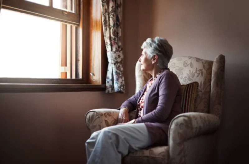 一人で窓の外を見つめる高齢者