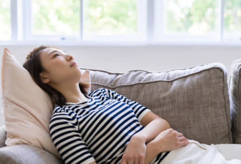 疲れた女性がソファで休んでいる様子