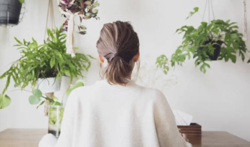 女性が観葉植物に囲まれた部屋に座る