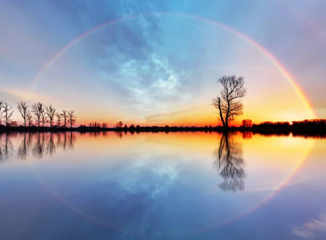 夕焼け空に虹がかかる湖畔の風景