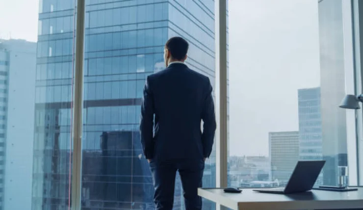 ビジネスマンが窓から都市を眺める