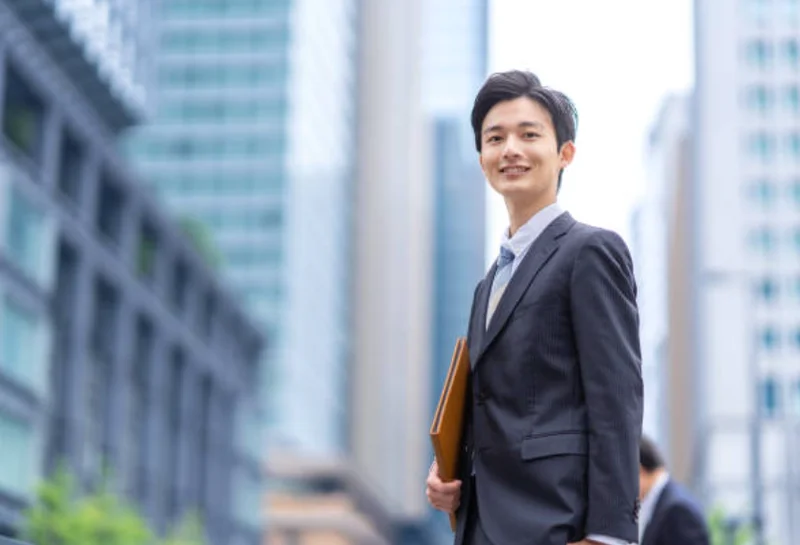 ビジネスマンがビル街でファイルを持つ
